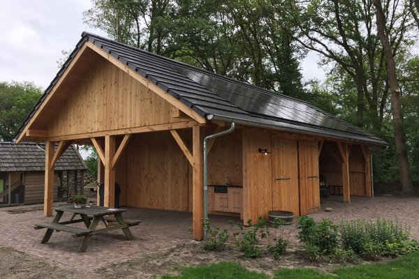 Strakke houten landelijke schuur met zolder en zonnepanelen en overkapping  