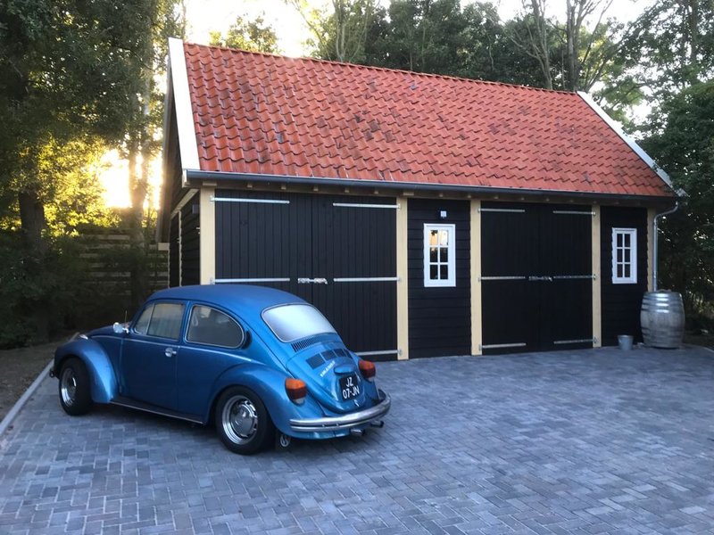 Zwarte houten garage in Dokkum met auto ervoor